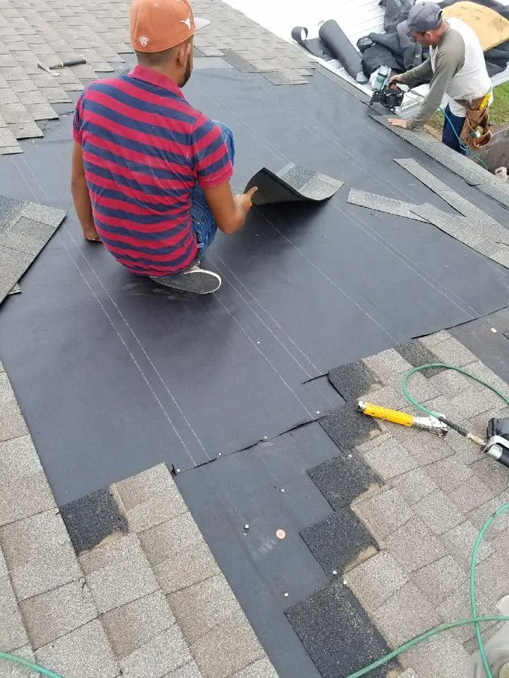 Diamond B crew rolling out underlayment and nailing down shingles on a roof