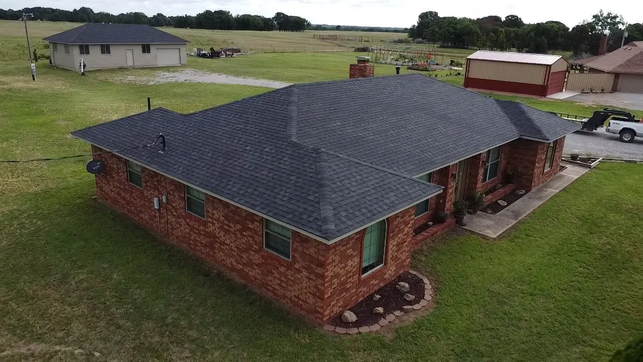 Aerial view of a newly shingled roof on a brick ranch house in the country