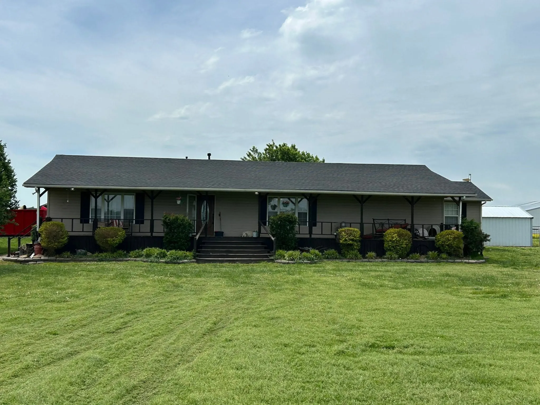 Finished dark shingle roof on a long country home with a covered porch